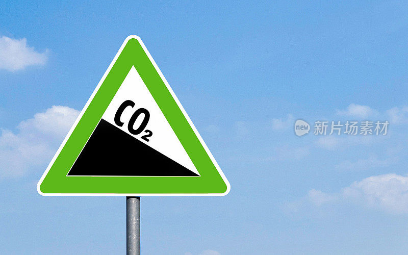 CO2 emission reduction sign green triangular shape against a clear blue sky